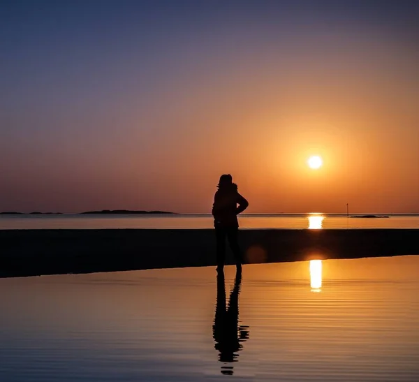 Reflet du coucher de soleil et d'une personne debout au bord de la plage dans l'eau — Photo