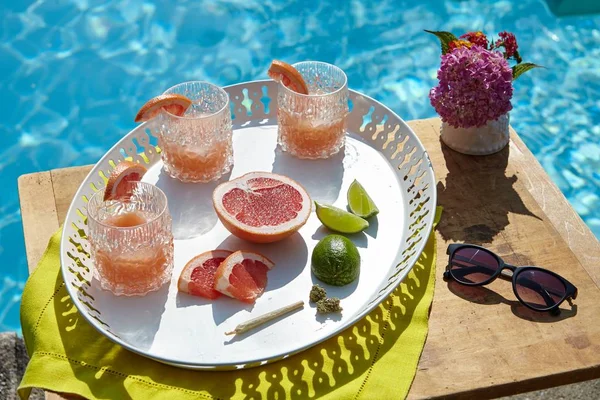 Hoge hoek close-up shot van een dienblad met grapefruit cocktails in de buurt van het zwembad — Stockfoto