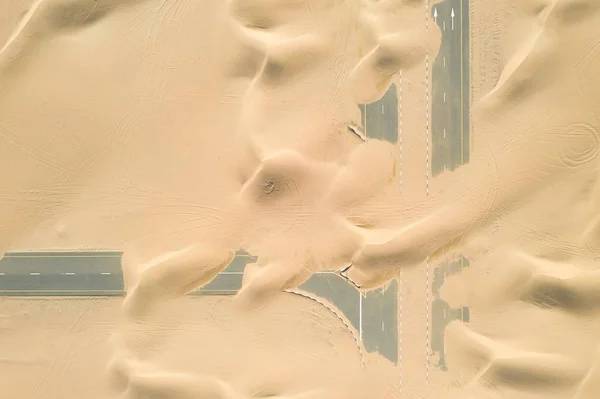 Primer plano de carreteras de construcción inacabada cubiertas por las arenas del desierto — Foto de Stock
