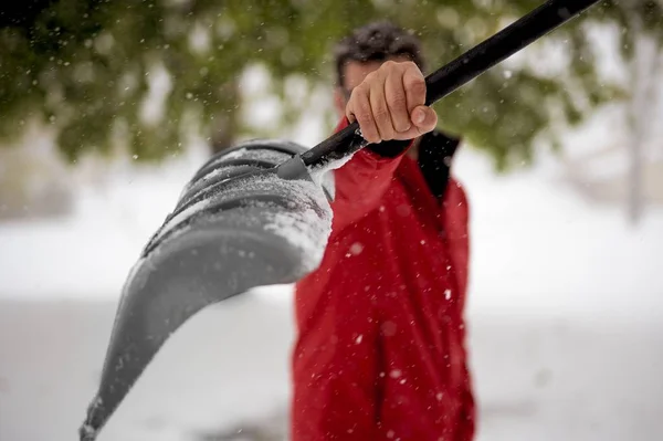 背景がぼやけているカメラに向かって雪のシャベルを保持している男性のクローズアップショット — ストック写真