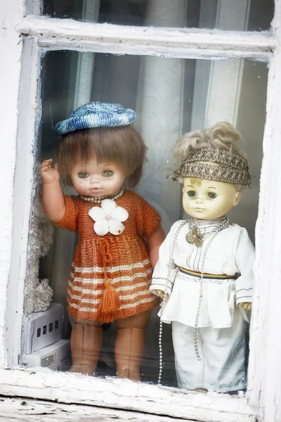 Tiro vertical de duas bonecas usando roupas laranja e branca perto da janela — Fotografia de Stock