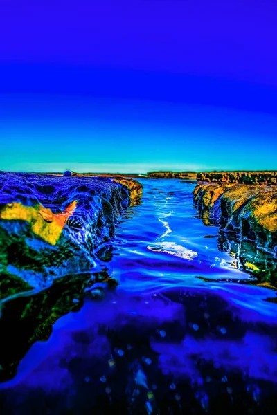 Вертикальний знімок гірських утворень посеред моря з надзвичайними кольорами — стокове фото