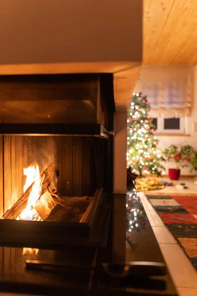 Lareira queimando dentro de uma lareira com a árvore de Natal decorada no fundo — Fotografia de Stock