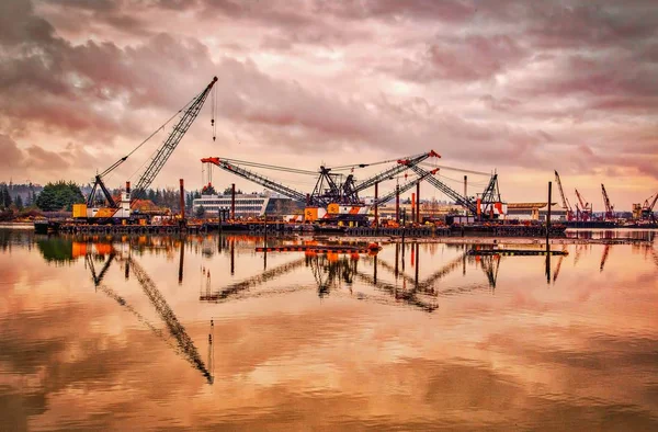 Reflexe stavebního zařízení ve vodě pod zataženou oblohou — Stock fotografie