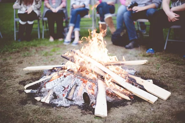 A closeup shot of a fire camp with people sitting around it