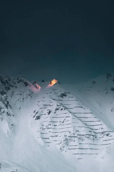 Egy Függőleges Lövés Egy Megvilágított Ház Tetején Egy Hófödte Hegycsúcs — Stock Fotó