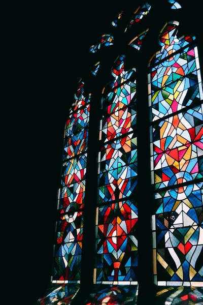 Vertical shot of mesmerizing glass window lighting up the dark room — Stock Photo, Image