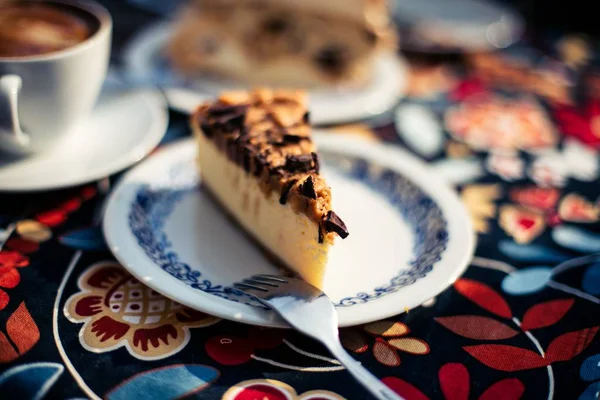 Közelkép egy szelet tortáról egy virágos asztali ruhán. — Stock Fotó
