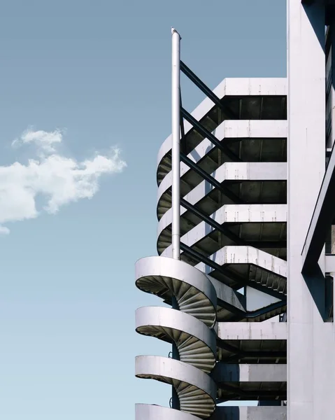 Tiro vertical de un edificio de metal y la escalera bajo el cielo azul — Foto de Stock