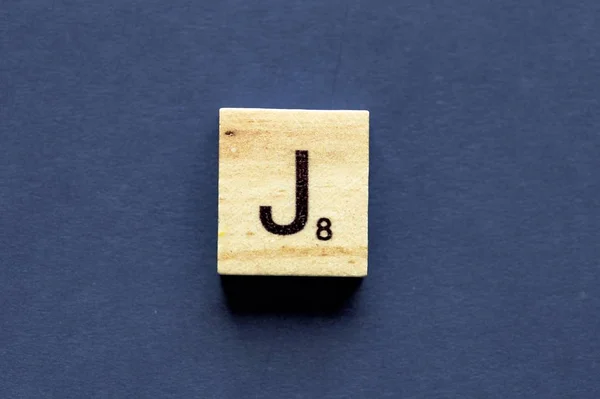 Carta J em um cubo de madeira de um jogo de tabuleiro wordplay — Fotografia de Stock
