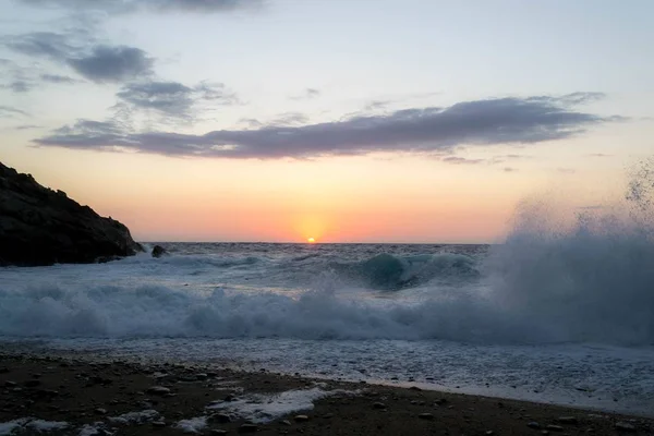 Tramonto mozzafiato che si riflette nell'oceano con onde che schizzano forte sulla riva — Foto Stock