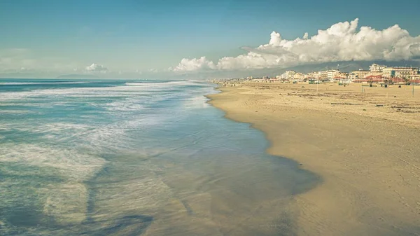 Hermosa playa cerca del mar tranquilo con un montón de edificios bajo el cielo nublado —  Fotos de Stock