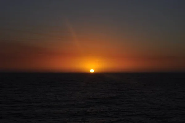 Dech beroucí snímek krásného západu slunce s pulzující teplé barvy přinášející krásu na pláž — Stock fotografie