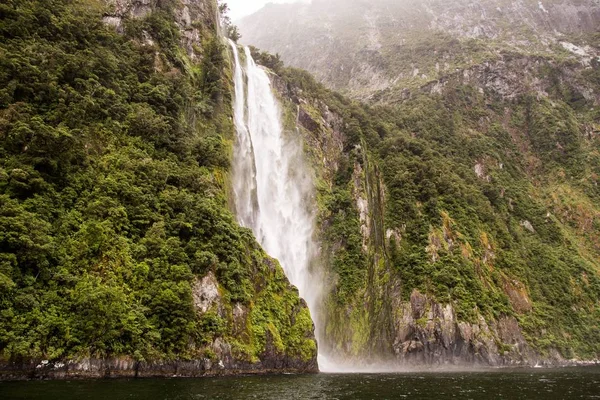 Bela cachoeira poderosa perto de formações rochosas cobertas com musgo — Fotografia de Stock