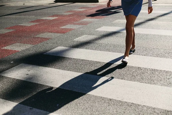 Frau überquert den Kreuzweg mit ihrem Schatten, der auf der Straße liegt — Stockfoto