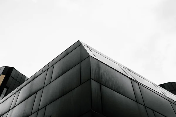 Balança cinzenta de baixo ângulo de um edifício geométrico sob o céu brilhante — Fotografia de Stock