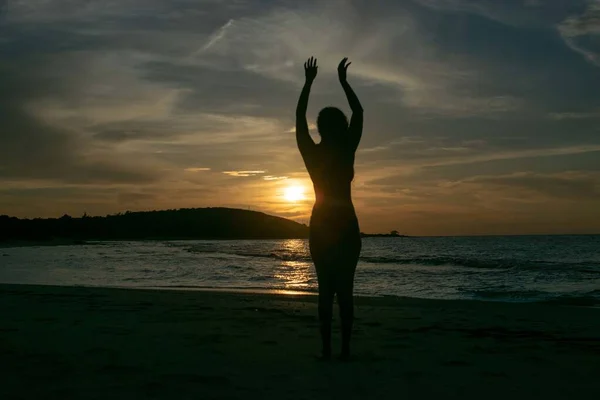 Silhouette d'une femelle debout dans l'eau de l'océan au coucher du soleil — Photo