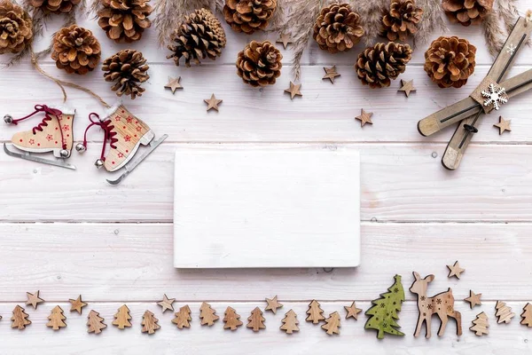 Pezzo di legno bianco bianco circondato da decorazioni natalizie su un tavolo di legno — Foto Stock