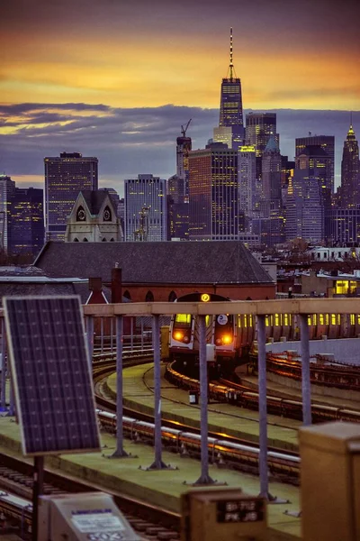 Stedelijk gebied met een trein op de spoorwegen omgeven door moderne wolkenkrabbers tijdens een prachtige zonsondergang — Stockfoto