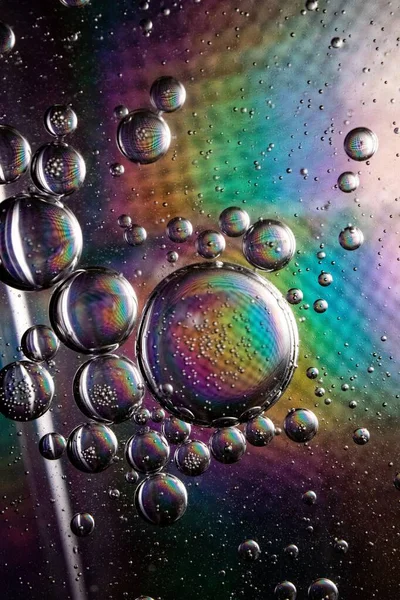Tiro vertical de burbujas de jabón sobre un fondo colorido con texturas interesantes —  Fotos de Stock