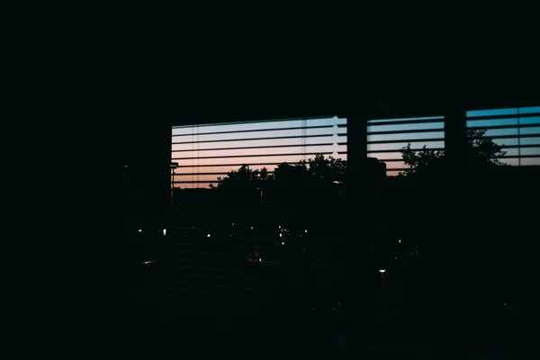 Persiana de ventana abierta con el paisaje urbano en el fondo por la noche —  Fotos de Stock