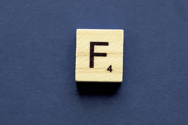 Letter F on a wooden cube from a wordplay board game — Stockfoto