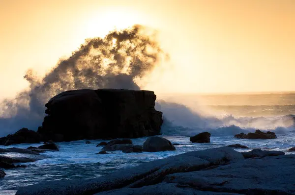 Bella vista delle onde del mare che colpiscono una grande pietra vicino alla spiaggia sotto il tramonto — Foto Stock