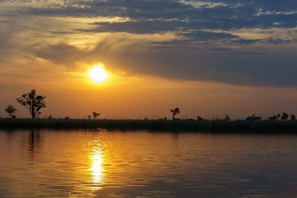太陽と木々が水面に映る夕日の美しい景色 — ストック写真