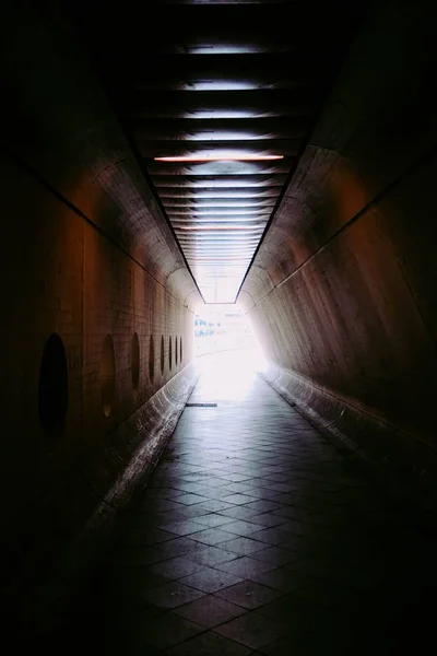 Vertikale Aufnahme des Lichts am Ende des gepflasterten Tunnels — Stockfoto