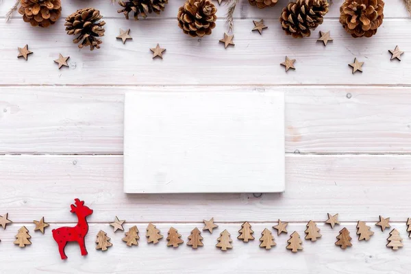 Κενό λευκό κομμάτι ξύλου που περιβάλλεται από μικρές χριστουγεννιάτικες διακοσμήσεις σε ξύλινο τραπέζι — Φωτογραφία Αρχείου