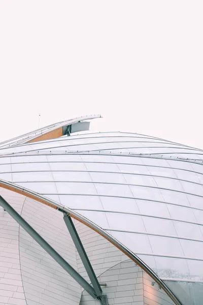Look close-up de um edifício moderno com janelas de vidro branco sob um céu cinza — Fotografia de Stock