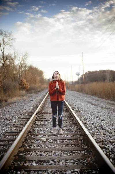 Tiro vertical de uma fêmea rezando enquanto estava nos trilhos do trem — Fotografia de Stock