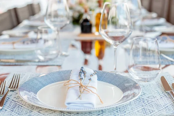 Ajuste de mesa de vacaciones con platos blancos y azules, servilletas plegadas y copas de vino — Foto de Stock