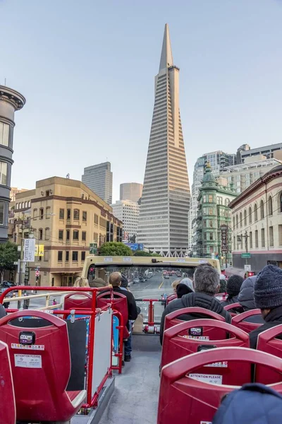 Röd turistbuss ridning i San Francisco under en blå himmel med moderna skyskrapor runt den — Stockfoto