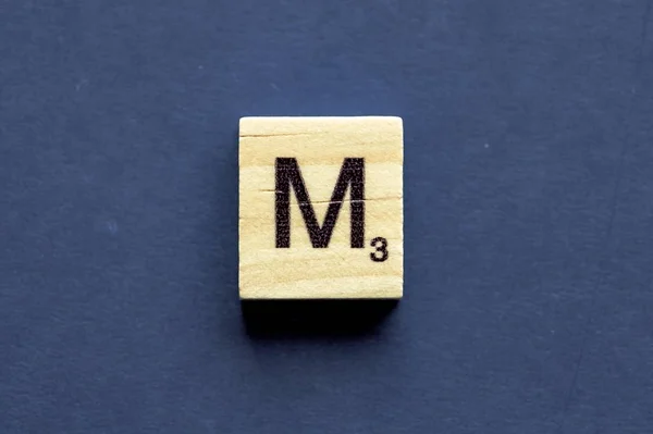Carta M em um cubo de madeira de um jogo de tabuleiro wordplay — Fotografia de Stock