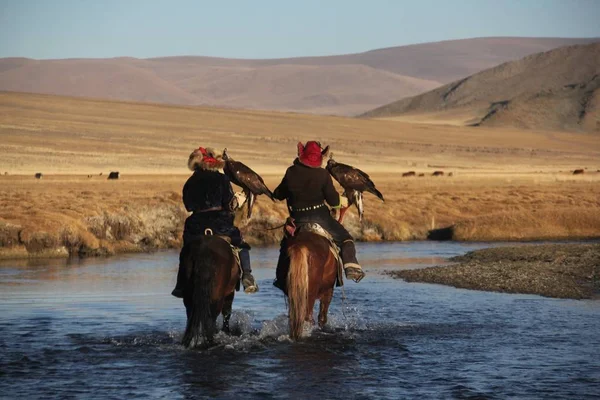 Foto di due cavalieri in un fiume circondato da una valle con colline su uno sfondo sfocato — Foto Stock