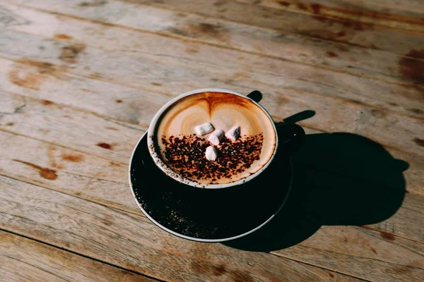 Secangkir macchiato espresso panas dengan marshmallow dan coklat di atasnya di atas meja kayu — Stok Foto