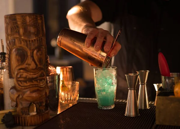 A tiki cocktail is mixed on a bartop.
