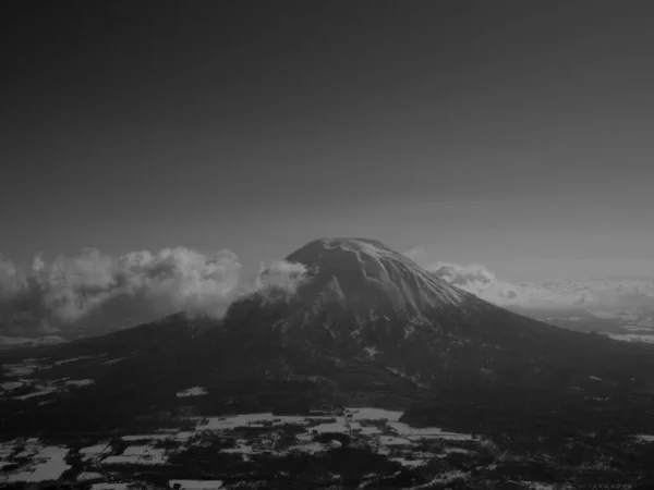 与蓬松的云彩混合在一起的山的灰蒙蒙的风景 — 图库照片