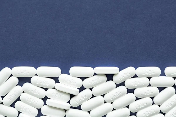 Close-up shot van witte pillen op een donkerblauw oppervlak - geweldig voor de achtergrond — Stockfoto