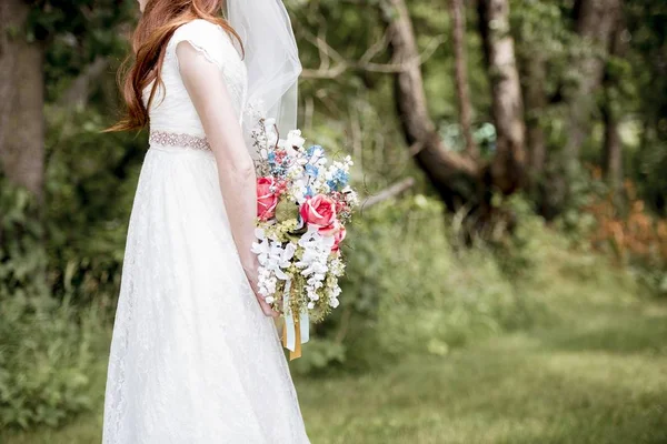 Неглибокий фокус знімок нареченої, що тримає за собою букет квітів — стокове фото