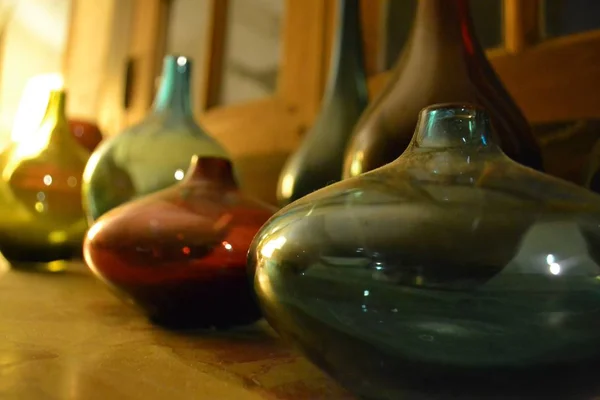Poucos frascos coloridos velhos cheios de líquido em uma mesa de madeira com um fundo embaçado — Fotografia de Stock