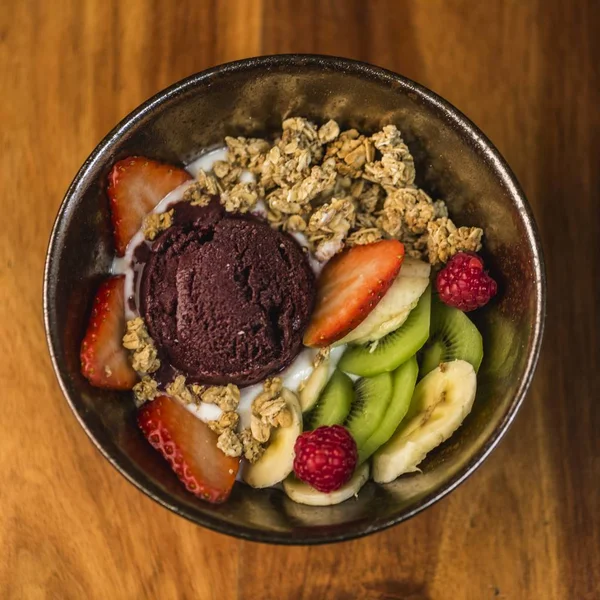 Deliciosa tigela de iogurte, sorvete, nozes e frutas frescas em uma superfície de madeira — Fotografia de Stock