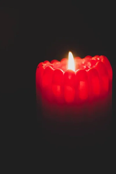 Detailní záběr rozsvícené červené svíčky s křivkami na černém pozadí — Stock fotografie