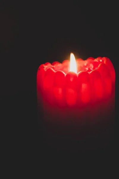 Imagem de close-up de uma vela vermelha acesa com curvas em um fundo preto — Fotografia de Stock