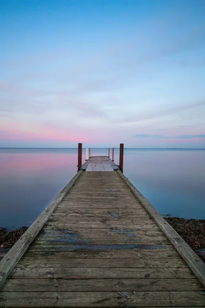 Plan vertical d'une longue jetée en bois près de l'océan sous le ciel pastel — Photo