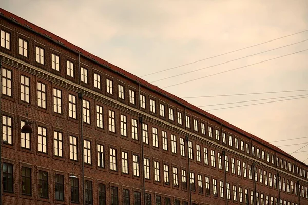 Brown grand bâtiment moderne avec fenêtres sous un ciel nuageux pendant le coucher du soleil — Photo