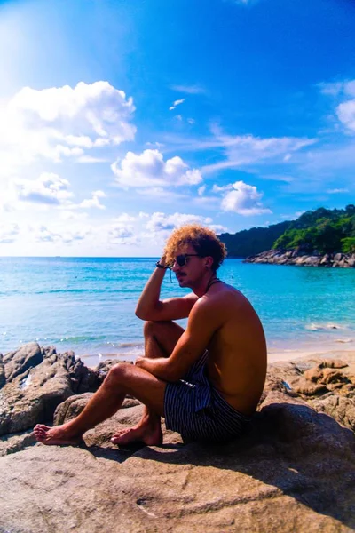 Pionowe Ujęcie Atrakcyjnego Mężczyzny Siedzącego Plaży Cieszącego Się Zapierającym Dech — Zdjęcie stockowe