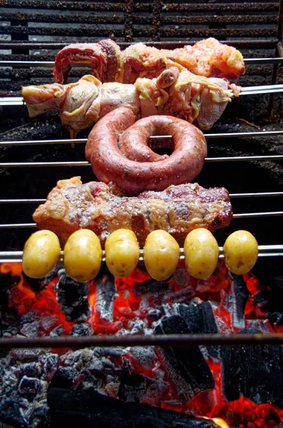 Verticale hoge hoek schot van vlees en aardappelen wordt gebarbecued op een barbecue grill. — Stockfoto