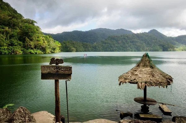 Una sombrilla tejida cerca del lago rodeada de altas montañas en Dumaguete, Filipinas — Foto de Stock